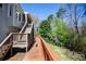 Wooden back deck with stairs and railings, surrounded by lush greenery and mature trees at 959 Hampton Nw Trl, Lilburn, GA 30047