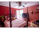 Bedroom with bright red walls featuring a four poster bed and ceiling fan at 959 Hampton Nw Trl, Lilburn, GA 30047