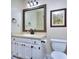 A quaint bathroom with a white vanity, framed mirror, and updated black fixtures, alongside white walls at 684 Oak Moss Dr, Lawrenceville, GA 30043