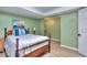 A delightful bedroom with calming green walls, wood floors, and a wood-frame bed with blue accents at 684 Oak Moss Dr, Lawrenceville, GA 30043