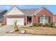 Charming brick home with an attached garage, manicured landscaping, and an American flag at 507 Mockingbird Ln, Loganville, GA 30052