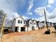 Long street view of new townhouses with garages and white and gray facades under a blue sky at 11618 E Lovejoy Rd, Hampton, GA 30228