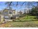 Lovely backyard with large lawn, mature trees, and deck leading to the yellow home at 1989 Mount Vernon Rd, Atlanta, GA 30338