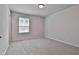 Bright, carpeted bedroom features a window providing natural light and a neutral color palette at 220 Eastmark Way, Fayetteville, GA 30214