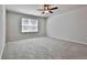 Carpeted bedroom with a ceiling fan and large window, creating a bright and relaxing atmosphere at 220 Eastmark Way, Fayetteville, GA 30214