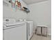 Laundry room with a white washer and dryer, wire shelving, and neutral colored tile flooring at 220 Eastmark Way, Fayetteville, GA 30214