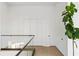 Hallway features wood floors, black metal and glass railing, three white doors, and an accent plant at 1051 Wimberly Ne Rd, Brookhaven, GA 30319