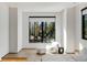 Modern sitting area with a fluffy chair, ottoman, side table, hardwood floors and a large window with wooded scenery at 1051 Wimberly Ne Rd, Brookhaven, GA 30319