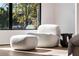 Modern sitting area featuring an ultra plush white chair and ottoman, with a side table and view of a sunny, wooded scene at 1051 Wimberly Ne Rd, Brookhaven, GA 30319