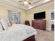 This light-filled main bedroom features tray ceilings, plush carpet, and a large dresser with a flatscreen TV at 1358 Magnolia Path Way, Sugar Hill, GA 30518