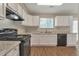 Spacious kitchen with white cabinetry, black appliances, and wood flooring at 1575 Kelleys Close, Stone Mountain, GA 30088