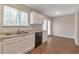 Open kitchen with white cabinets, black appliances, and wood flooring leading to dining area at 1575 Kelleys Close, Stone Mountain, GA 30088