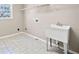 Bright laundry room features a utility sink, tiled floor, and convenient upper shelving for storage at 4312 White Hickory Nw Ln, Kennesaw, GA 30152