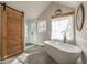 Elegant bathroom with a freestanding tub, a sliding barn door, and a glass shower at 210 Barrett Springs Way, Canton, GA 30115