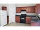 Well-lit kitchen features wooden cabinets, dark countertops, white refrigerator, and black appliances at 2102 Executive Dr, Duluth, GA 30096