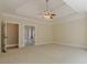 Carpeted bedroom with tray ceiling, ceiling fan, and multiple doorways at 7085 Wakehurst Pl, Cumming, GA 30040