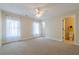 Neutral bedroom with carpet, windows with white curtains, and ensuite bathroom at 7085 Wakehurst Pl, Cumming, GA 30040