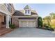 Attached two car garage with brick facade, dormer, and lovely landscaping at 7085 Wakehurst Pl, Cumming, GA 30040