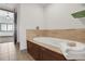 Bathroom with a modern soaking tub, tile accents, and a door leading to the bedroom at 4561 Olde Perimeter Way # 702, Atlanta, GA 30346