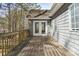 View of a wooden deck with double doors leading into a grey home surrounded by trees at 55 Legend Creek Cove, Douglasville, GA 30134