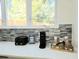 Bright kitchen features a tiled backsplash, black toaster and coffee maker on a quartz countertop at 245 Mathewson Pl, Atlanta, GA 30314