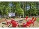 Backyard with gravel firepit surrounded by red Adirondack chairs and outdoor movie screen at 3034 Bristlewood Nw Ln, Marietta, GA 30064