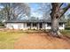Charming white brick home featuring dark trim, decorative lattice, and manicured front lawn with mature trees at 1199 Murray Sw Cir, Marietta, GA 30064