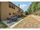 Backyard featuring a concrete patio, a table and chair set, grass, and a stone embankment with trees at 1249 Austin Thomas Dr, Dacula, GA 30019