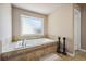 Bathroom featuring a built-in bathtub with tile surround and a large window for natural light at 1249 Austin Thomas Dr, Dacula, GA 30019