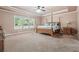 Spacious main bedroom featuring a ceiling fan, carpet floors, large windows and a four-post wooden bed frame at 1249 Austin Thomas Dr, Dacula, GA 30019