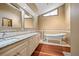 Bathroom featuring granite vanity, white soaking tub, and wood flooring at 2050 Plantation Rd, Lawrenceville, GA 30044