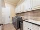 Bright laundry room featuring white cabinets, stainless steel washer and dryer, sink and tile backsplash at 3284 Kylee Dawn Cir, Lawrenceville, GA 30045