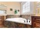 Jetted soaking tub is framed by decorative tile, storage cabinets and a stained-glass window at 3284 Kylee Dawn Cir, Lawrenceville, GA 30045
