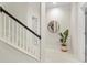 Bright hallway featuring carpeted stairs with a black handrail, a round mirror and a decorative plant at 3640 Ridgeway Ter, Suwanee, GA 30024