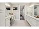 Bright bathroom with dual vanity, white cabinets, and a doorway leading to a walk-in closet and bedroom at 55 Church St, Alpharetta, GA 30009