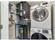 Laundry and utilities closet featuring a stacked washer/dryer, shelving, and a hot water heater at 1100 Howell Mill Nw Rd # 613, Atlanta, GA 30318
