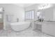 This stylish bathroom includes a free-standing tub, marble floors, double-sink vanity, and bright modern lighting at 5425 Edinbourgh Ct, Cumming, GA 30040