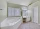 Bright bathroom features a large soaking tub, white cabinets, and plantation shutters at 5425 Edinbourgh Ct, Cumming, GA 30040