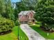 Charming brick home with a two-car garage, lush green lawn, and mature trees at 5425 Edinbourgh Ct, Cumming, GA 30040