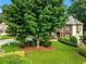 View of two-story brick home with mature trees, green lawn, and established landscaping at 5425 Edinbourgh Ct, Cumming, GA 30040