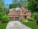 Two-story brick home with attached two-car garage and manicured lawn at 5425 Edinbourgh Ct, Cumming, GA 30040