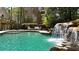 Gorgeous pool with a rock waterfall feature and a luxury outdoor seating area on the pool deck at 1112 Kensington Ct, Johns Creek, GA 30022