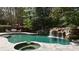 Backyard pool with a stone waterfall feature and cozy outdoor seating area at 1112 Kensington Ct, Johns Creek, GA 30022