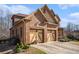 Elegant brick home showing a three-car garage, landscaped yard, and architectural details, blending comfort with sophistication at 117 Olde Heritage Way, Woodstock, GA 30188