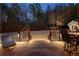A well lit backyard deck featuring a relaxing lounge chair, outdoor dining set, and manicured landscaping at 340 Housman Dr, Fayetteville, GA 30215