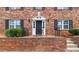 Close-up of the red brick building with a decorative entrance, black door, black iron railings, and trimmed shrubbery at 3665 Chestnut Dr # A2, Atlanta, GA 30340
