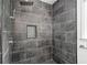 Modern shower with grey tile, a built-in shelf, and a rainfall shower head at 3040 Wax Wing Nw Ct, Kennesaw, GA 30144
