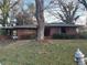 A single story brick home with a carport sits on a lot with mature trees needing some landscaping at 1713 Cahoon St, Atlanta, GA 30310