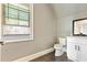 Bathroom featuring a toilet and vanity with white cabinets, complemented by grey tiled floors and a window view at 5241 Moon Rd, Powder Springs, GA 30127