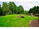 Sprawling backyard features lush green grass, mature trees, and a playground area, ideal for outdoor fun at 6040 Boulder Bluff Dr, Cumming, GA 30040